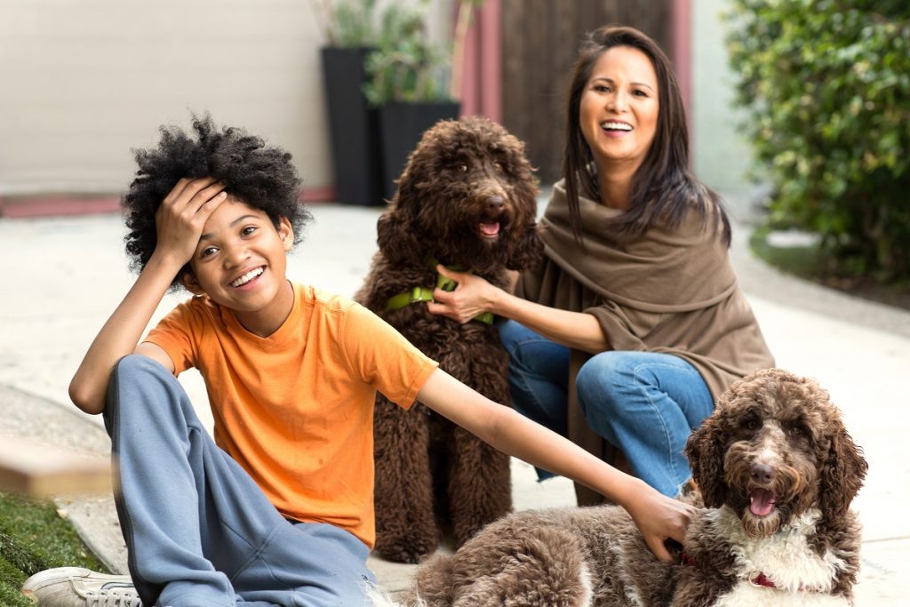Mother and her son laughing and playing with their dog.